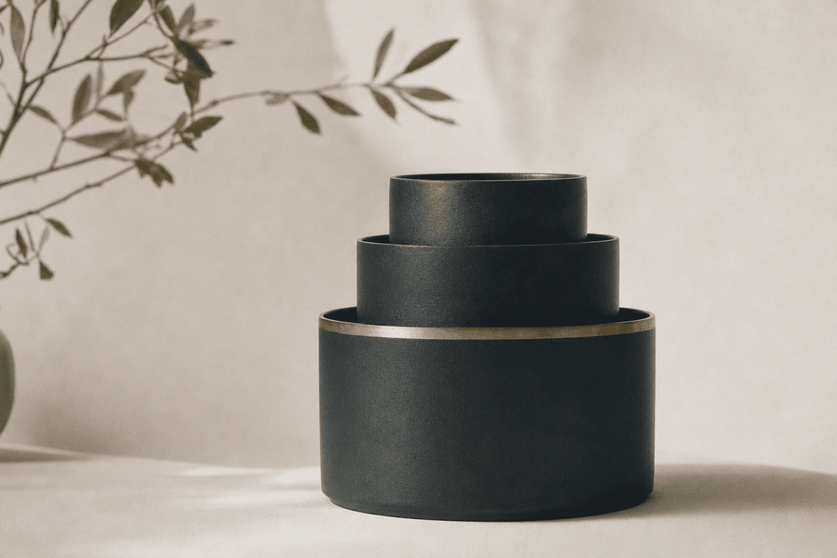 Three nested deep teal vessels of ascending size with brass rim, soft natural light.